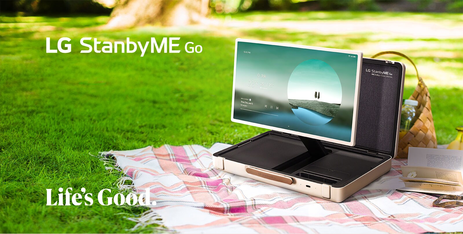LG StanbyME Go is placed on a checkered picnic blanket with left side forward, displaying a weather themed home screen.