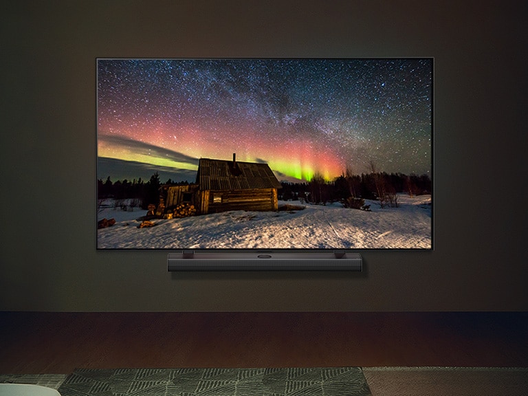 Ein LG TV mit LG Soundbar in einem modernen Wohnraum bei Nacht. Wir sehen ein Bild der Aurora Borealis mit den idealen Helligkeitsstufen.