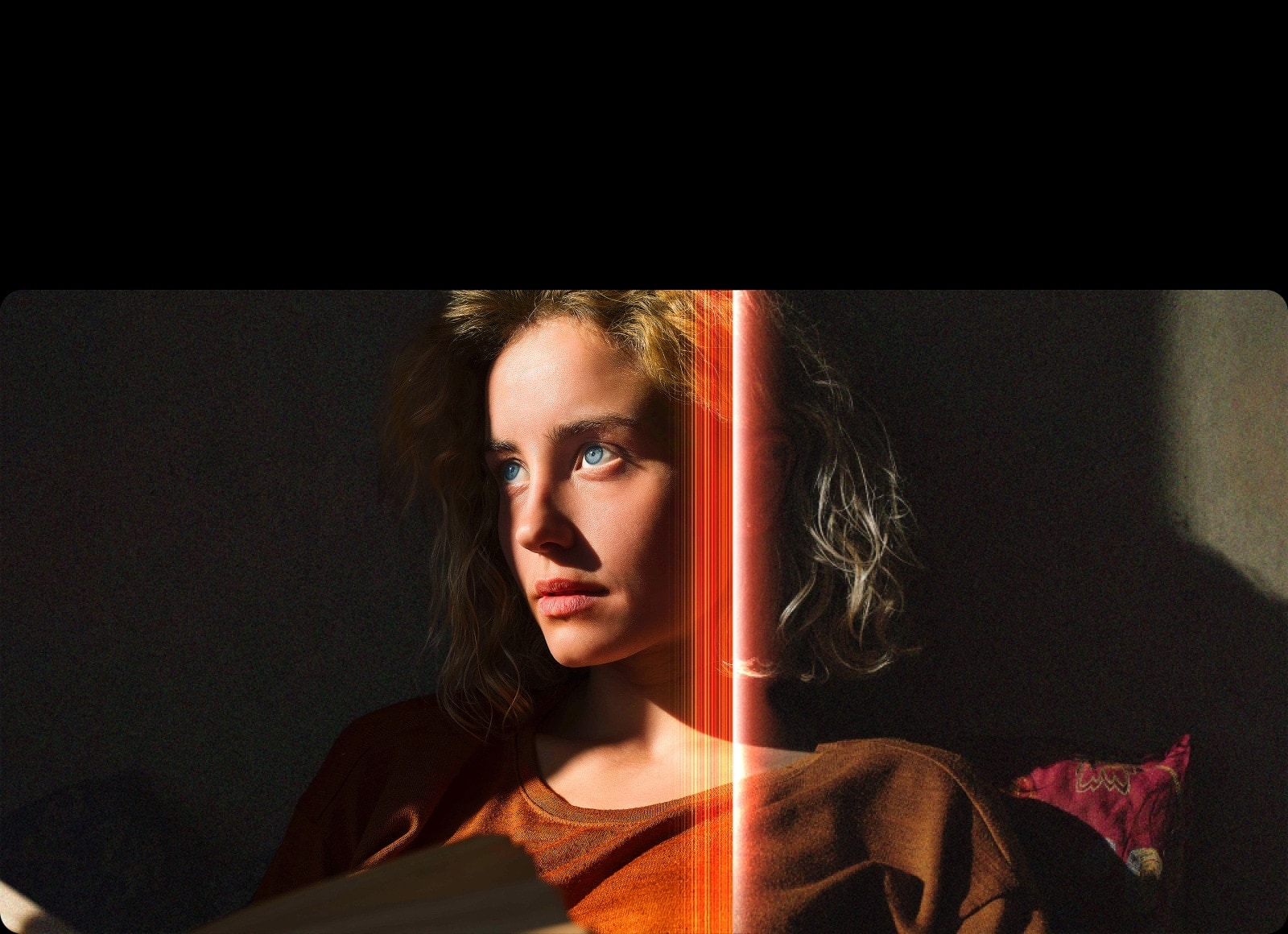 Eine Frau mit strahlend blauen Augen und einem orangefarbenen Oberteil in einem dunklen Raum. Rote Linien, die AI-Verfeinerungen darstellen, bedecken einen Teil ihres Gesichts, das hell und detailliert ist, während der Rest des Bildes stumpf aussieht. 