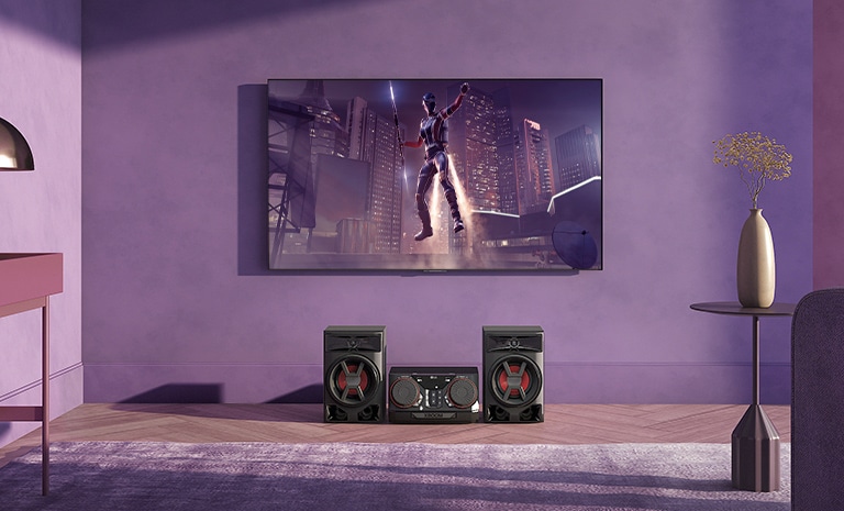 LG CK43N é colocado na sala de estar. Acima do alto-falante, a TV LG está pendurada na parede mostrando uma cena de filme.