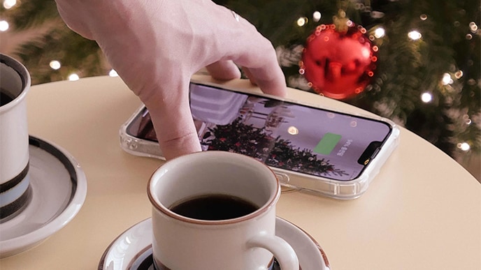 Using the charging function, a cell phone is placed on top of the product. There is a coffee cup next to it, showing it being used like a table.