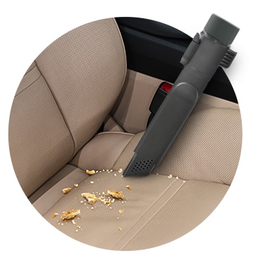 This image shows you cleaning the car seat with a Crevice Tool.