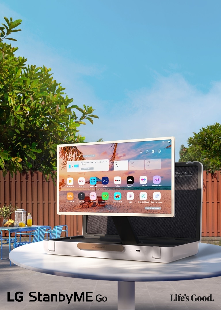 The LG StanbyME Go is placed right in the backyard with the right side forward. It displays the home screen.