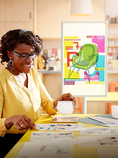 A design image of the chair is displayed on the StanbyME screen placed in the office, and a woman is meeting while looking at the paper.