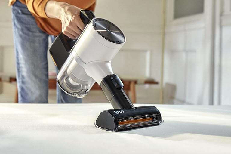 This image shows a Power Drive Mini being used to clean an animal hair and dusty sofa.