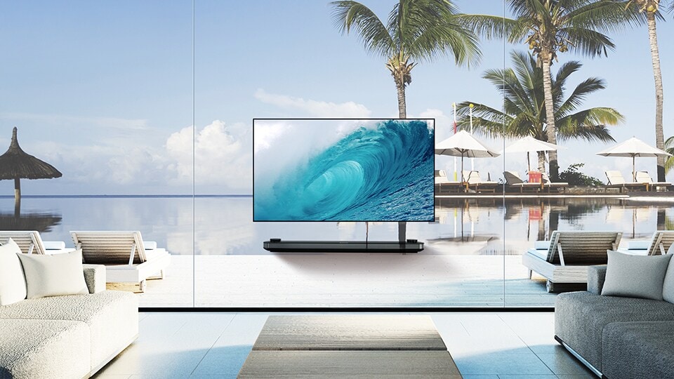 LG SIGNATURE OLED TV W is showing the cool wave on its screen while being laid in the living room with the blue ocean view beyond the window.  