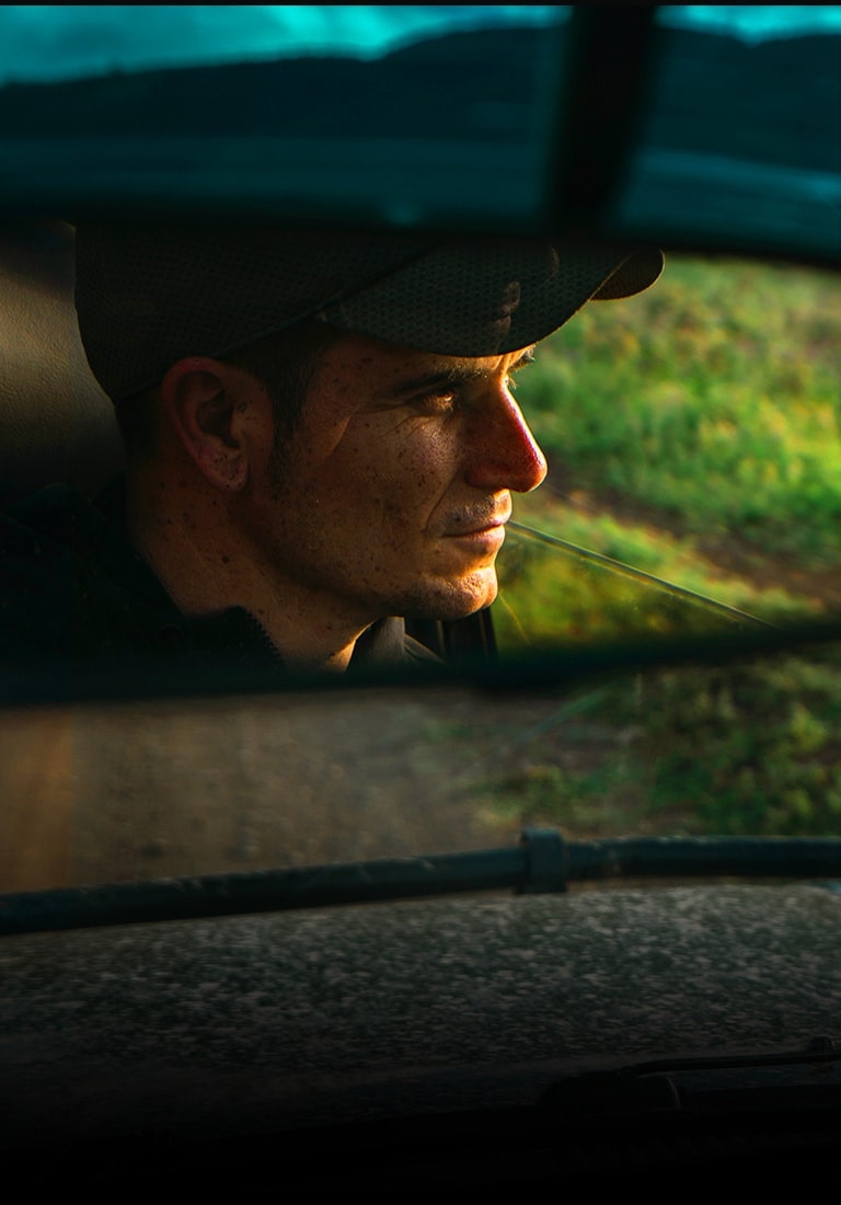 Riflesso di un uomo nello specchietto retrovisore di un’auto. L’inquadratura si allarga per mostrare la stessa scena sul TV QNED.
