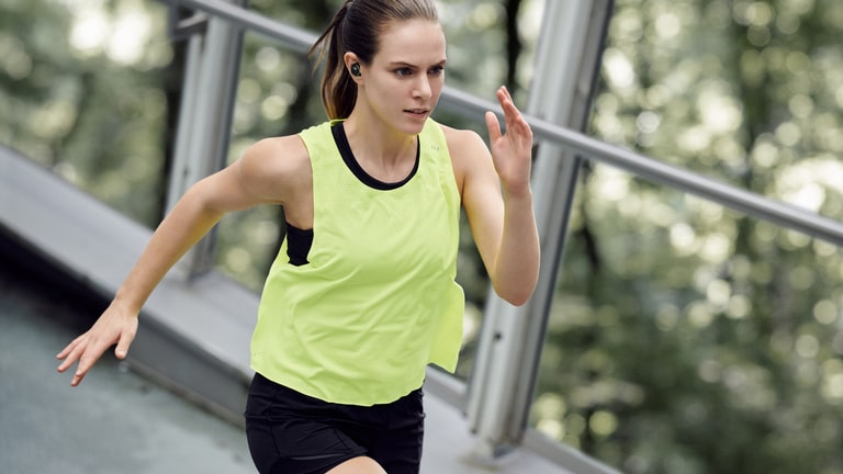 Musica per allenamento: donna che corre con cuffiette bluetooth LG per lo sport