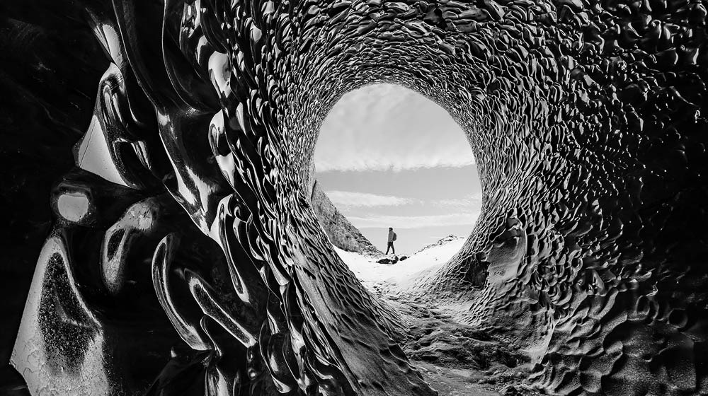 Un video di un uomo che fa un'escursione a piedi attraverso un tunnel scavato. Un cursore si muove sullo schermo, applicando un contrasto infinito all'immagine.