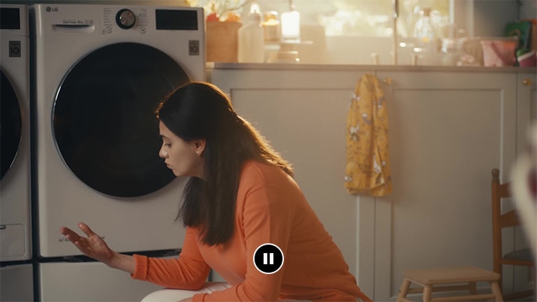 Mulher sentada em frente à máquina de lavar a olhar para as suas mãos molhadas
