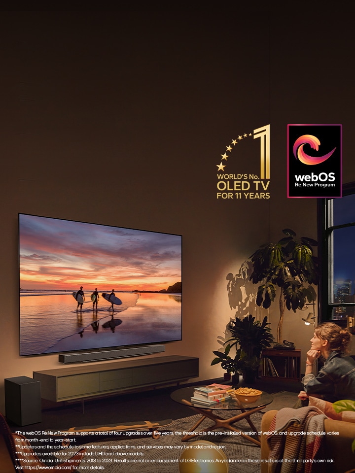 LG OLED evo C4 TV mounted on the wall of a cosy evening living room and an LG soundbar mounted just below it. On the TV, a beach at sunset with silhouttes of three surfers is displayed. Two women sit on the sofa facing and leaning towards the TV and soundbar. The "World's number 1 OLED TV for 11 Years" emblem and the "webOS Re:New Program" logo are in the image. A disclaimer reads: "The webOS Re:New Program supports a total of four upgrades over five years, the threshold is the pre-installed version of webOS, and upgrade schedule varies from month-end to year-start." "Updates and the schedule to some features, applications, and services may vary by model and region." "Upgrades available for 2023 include UHD and above models." "Source: Omdia. Unit shipments, 2013 to 2023. Results are not an endorsement of LG Electronics. Any reliance on these results is at the third party’s own risk. Visit https://www.omdia.com/ for more details."