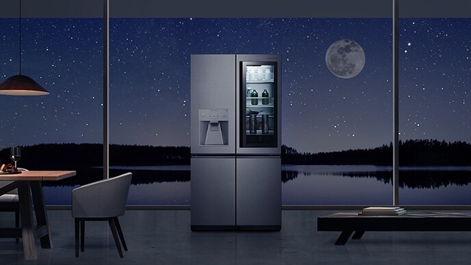 El refrigerador LG SIGNATURE se coloca justo en el medio de la casa con un paisaje iluminado por la luna más allá de la ventana.