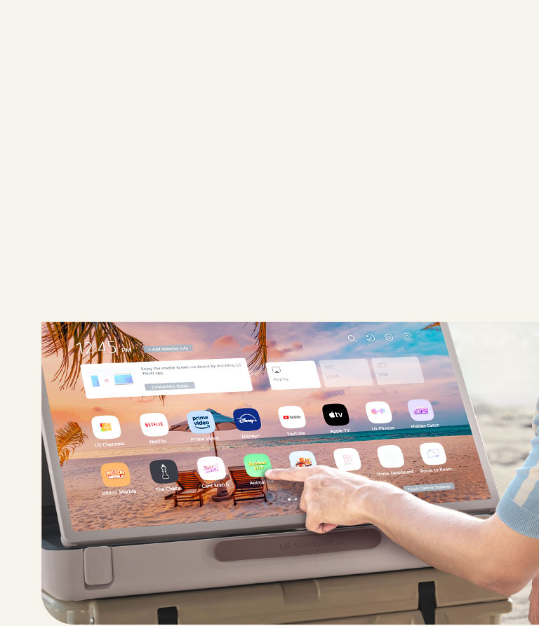 Close-up of LG StanbyME Go. The product is placed on a table, and the screen rotated horizontally. A hand is touching an icon.