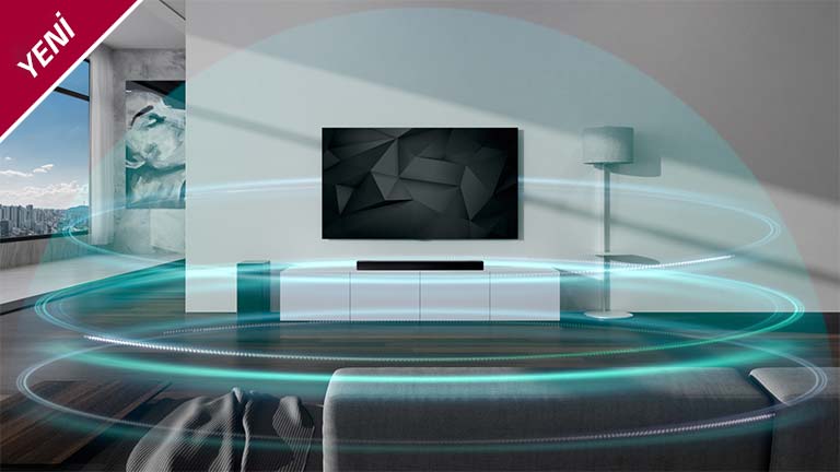 Mavi kubbe şeklindeki 3 katmanlı ses dalgaları, oturma odasındaki soundbar ve TV'yi kaplar. YENİ işareti sol üst köşede gösterilir.