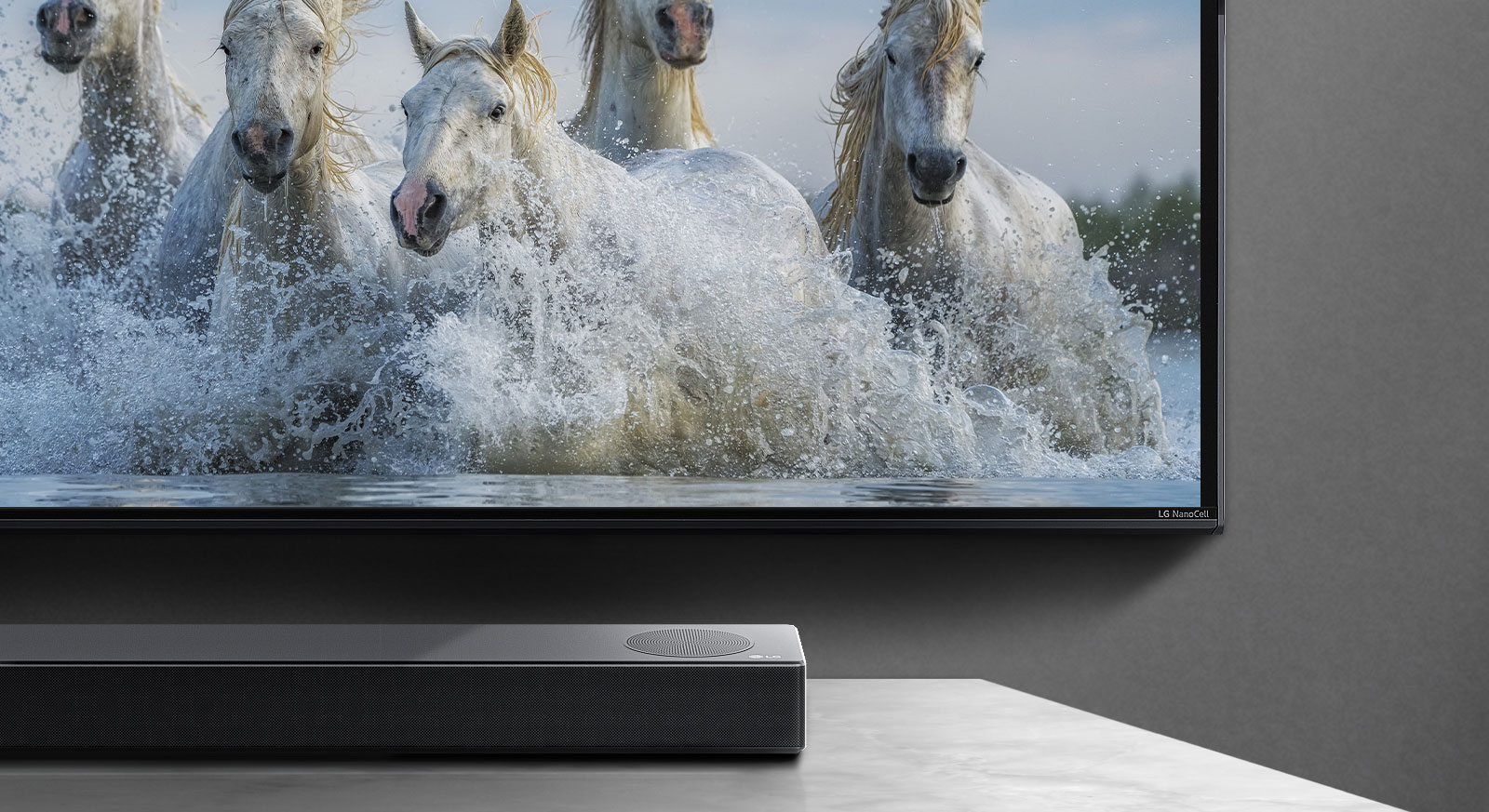 La mitad de la pantalla inferior y la mitad de la barra de sonido. El televisor muestra caballos blancos corriendo sobre el agua. 