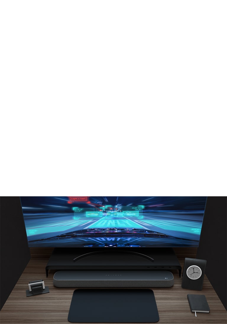 En lydplanke, en buet monitor, en lapp og en liten klokke er plassert på en trepult. Et racingspill spilles på skjermen for å beskrive dets spillvennlige funksjoner.