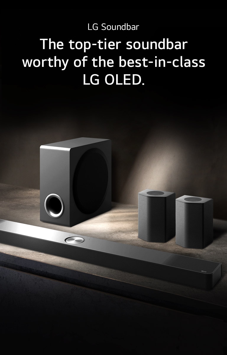 LG Soundbar, rear speakers, and subwoofer are placed within an angled perspective on a brown wooden shelf in a black room, enveloped in darkness with light only casting over the sound system.