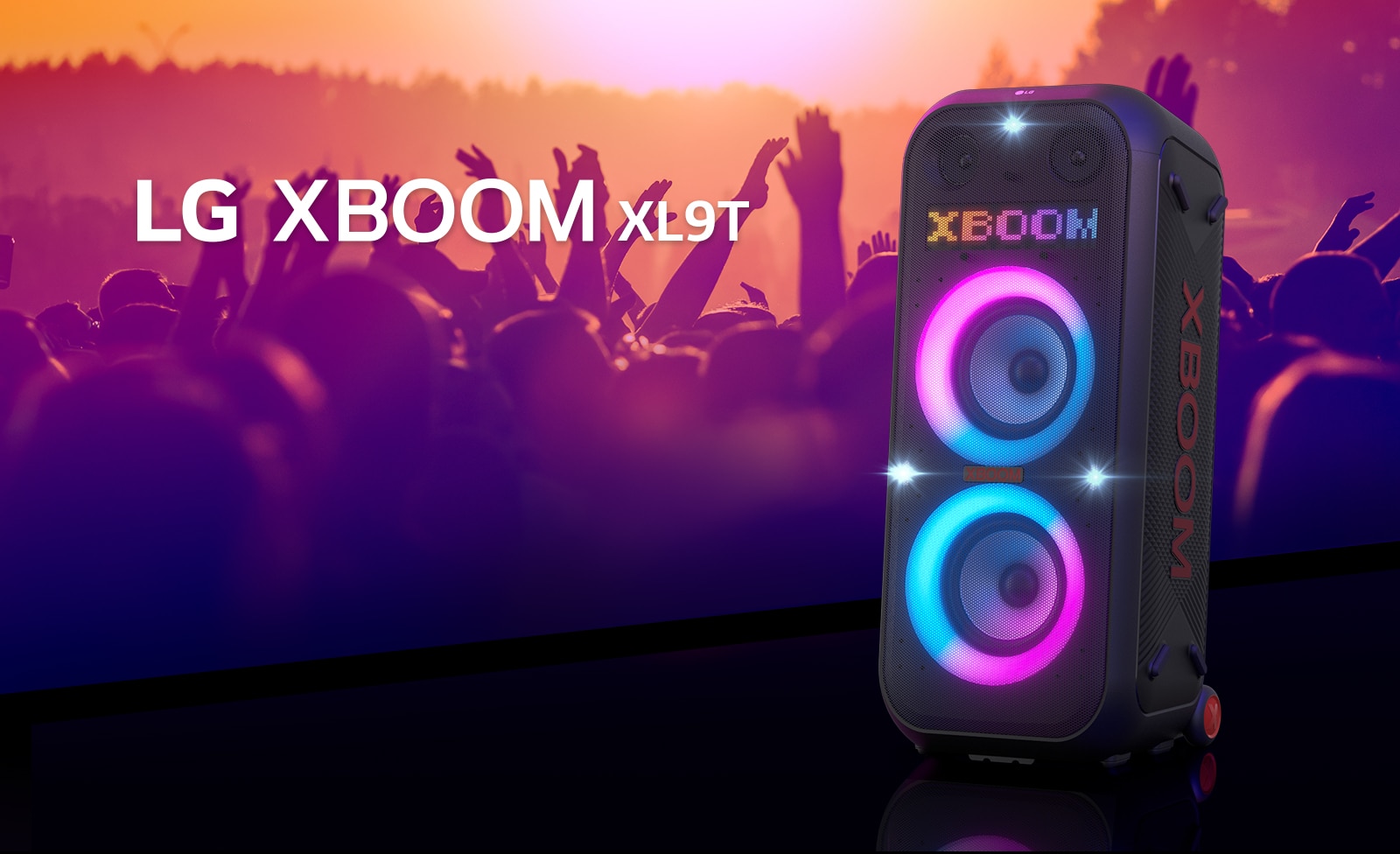 LG XBOOM XL9T is placed on the surface with diagonal view. Multi-color lighting on, and the display shows the word "XBOOM". Behind the speaker, shillouette of people enjoying party.