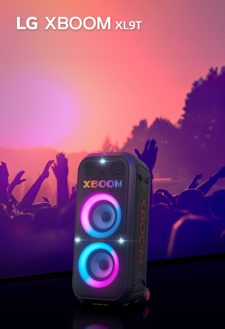LG XBOOM XL9T is placed on the surface with diagonal view. Multi-color lighting on, and the display shows the word "XBOOM". Behind the speaker, shillouette of people enjoying party.