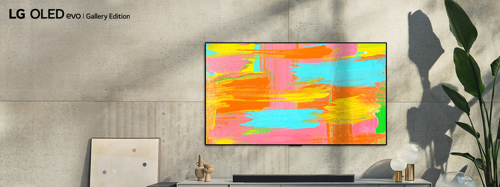 Zdjęcie telewizora LG OLED G2 zawieszonego na ścianie w minimalistycznie urządzonym szarym pokoju. Na ekranie jest wyświetlone jaskrawe abstrakcyjne dzieło sztuki. Nad zdjęciem znajduje się napis „Estetyka na najwyższym poziomie”.