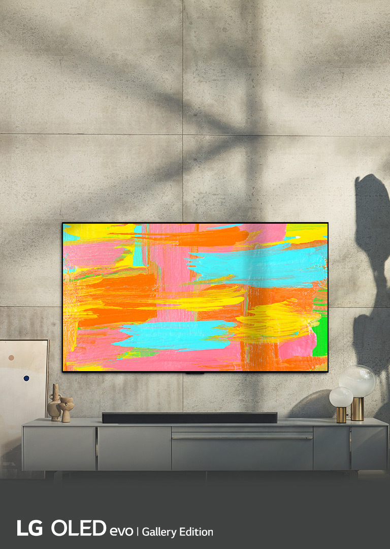 Zdjęcie telewizora LG OLED G2 zawieszonego na ścianie w minimalistycznie urządzonym szarym pokoju. Na ekranie jest wyświetlone jaskrawe abstrakcyjne dzieło sztuki. Nad zdjęciem znajduje się napis „Estetyka na najwyższym poziomie”.