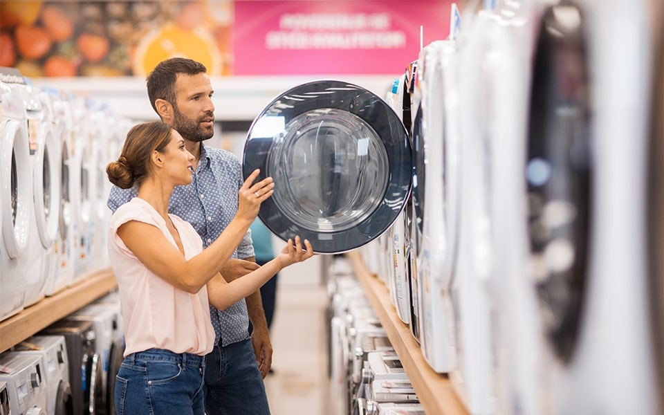 homem e mulher a olhar para uma máquina de lavar roupa