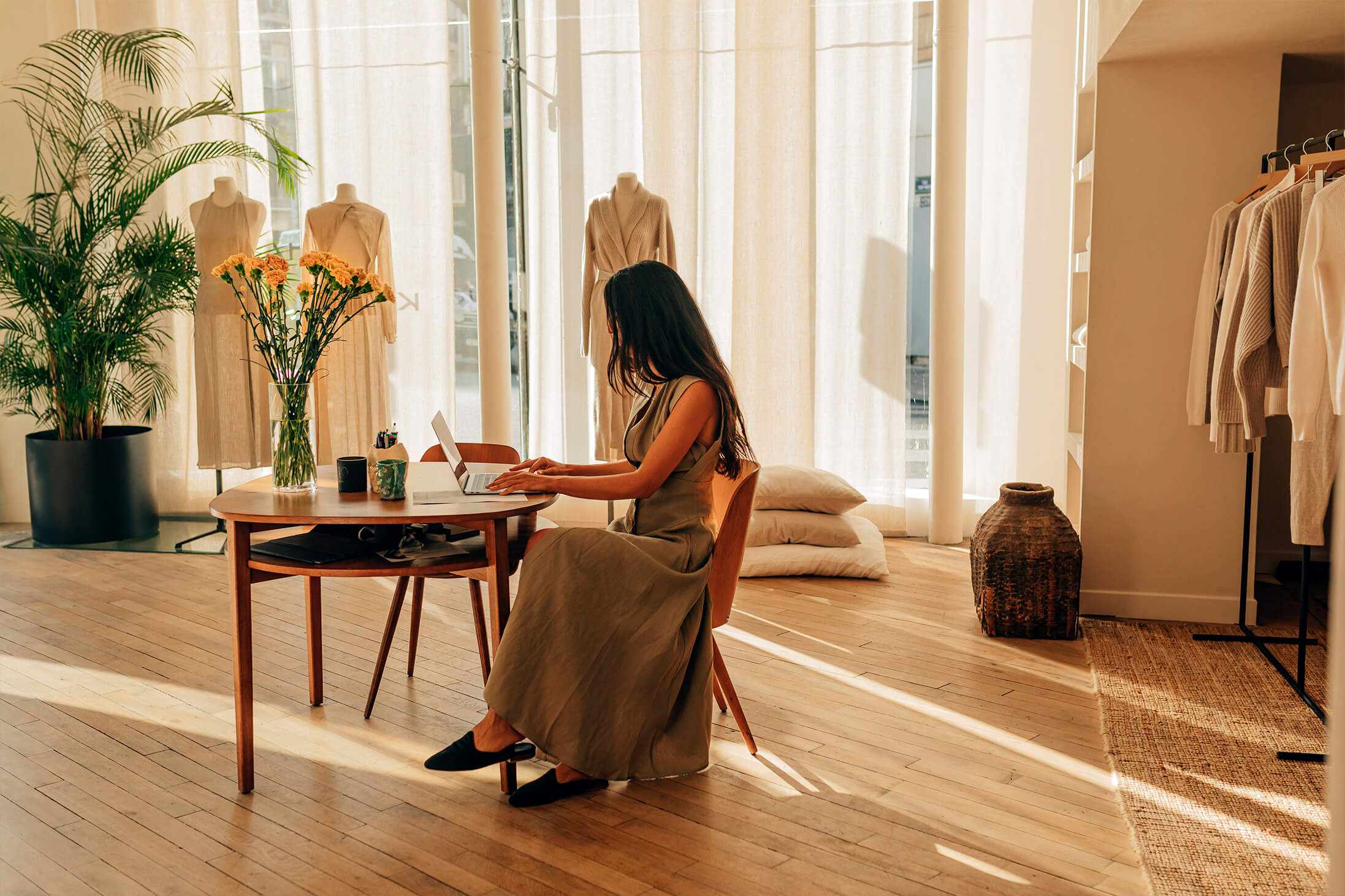 Bild des Designers von Le Kasha, der vor einem Tisch in einem warm beleuchteten Atelier sitzt.