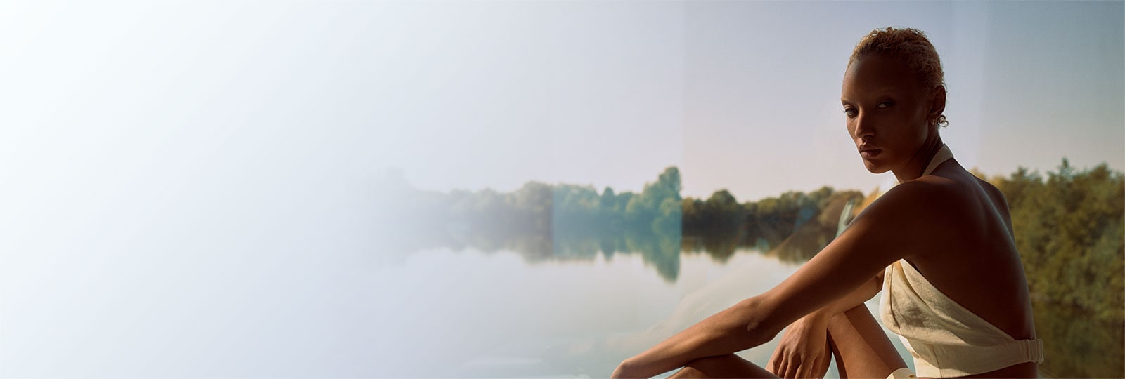 Bild eines Modells, das eines der Wintersonnenkapsel-Sammlungsstücke trägt, die vor einem schönen See sitzen.