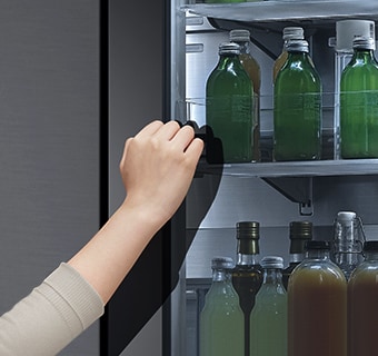 Hình ảnh phía trước của tủ lạnh InstaView kính màu đen với đèn bên trong. Bàn tay đang chạm vào màn hình InstaView.