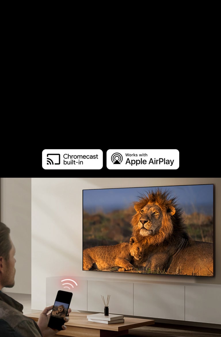 Một chiếc TV LG gắn trên tường trong phòng khách, trưng bày một con sư tử và sư tử con. Một người đàn ông ngồi ở phía trước với chiếc điện thoại thông minh trên tay hiển thị hình ảnh tương tự của những con sư tử. Hình ảnh ba thanh cong màu đỏ neon được hiển thị ngay phía trên điện thoại thông minh hướng về phía TV.