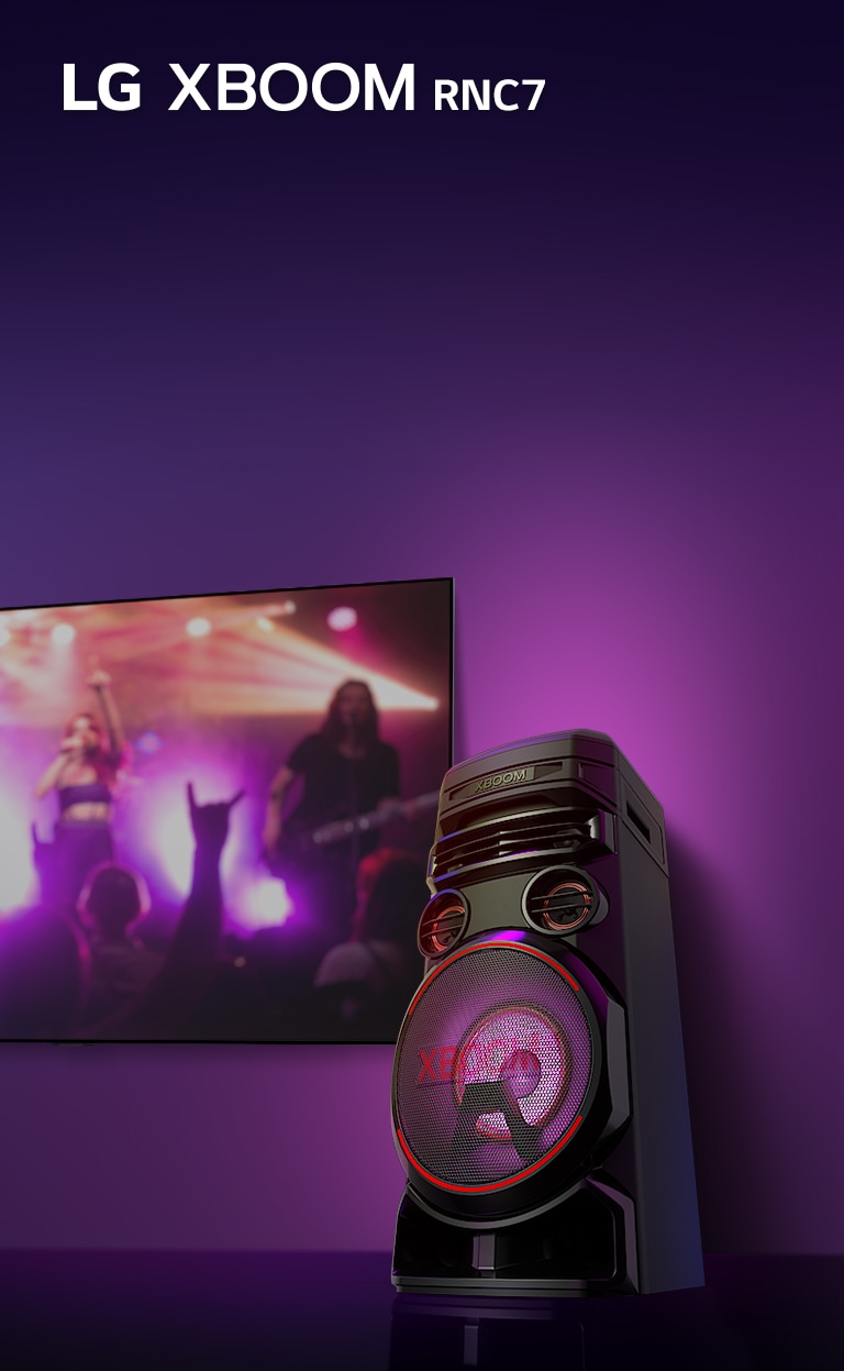 Hình ảnh ở góc thấp mặt bên phải của LG XBOOM RNC7 trên nền tím. Đèn XBOOM cũng có màu tím. Đồng thời màn hình TV hiển thị khung cảnh buổi hòa nhạc.