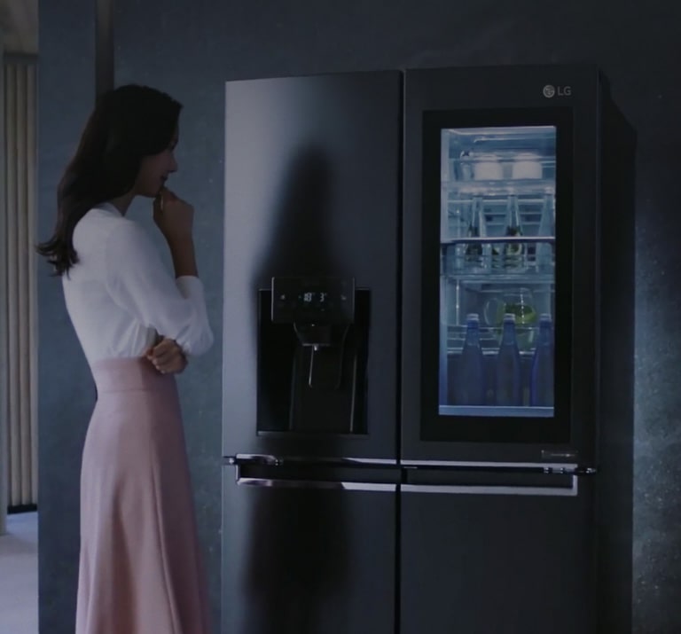 Hình ảnh một người phụ nữ đứng trước tủ lạnh.