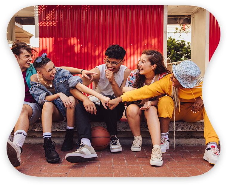 A group of friends in colorful clothing sits on the stairs, laughing and enjoying their time together.